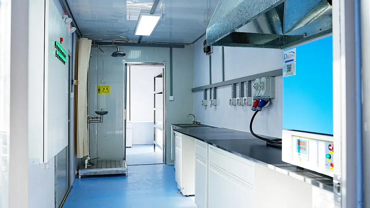 Australia Mobile Container Laboratory Project 2025 1 Interior of a DECENT Australia Mobile Container Laboratory Project 2025 wet lab, featuring a safety shower, eyewash station, sink, lab benches, and a blue furnace of lab equipment.