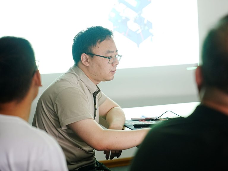 Qingdao Decent Group Engineer, Lv Yuan Rui, leading a product training session in a conference room with a presentation screen in the background.