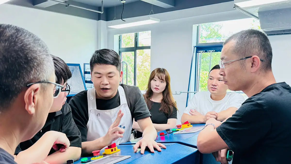 Revolutionizing Fire Assay: How China’s Premier Mining Lab Achieved 40% Efficiency Gains with Decent Group Semi-Automatic System插图5 A group of professionals engaged in a discussion or training session in a laboratory or industrial setting, focusing on collaboration and system implementation.