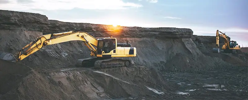 Large excavators operating in an open-pit mine at sunset, symbolizing DECENT's ore mining operations