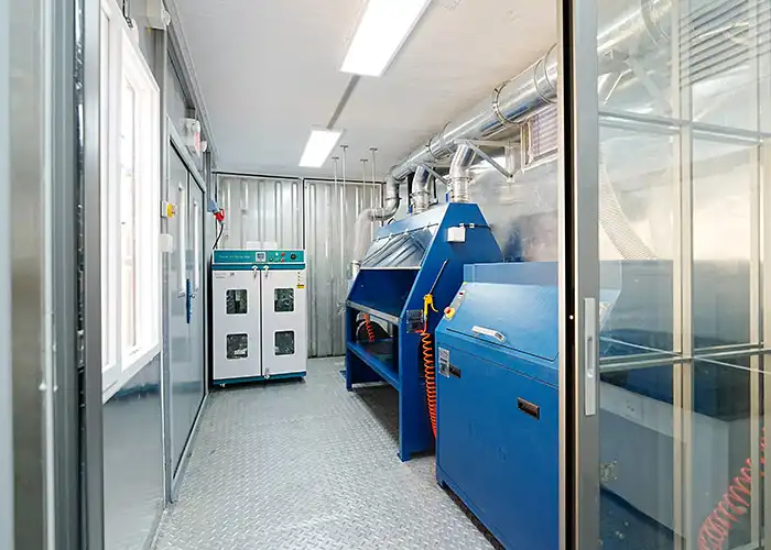 Interior view of Qingdao Decent Group's 20-foot mobile mineral processing lab, featuring blue processing equipment, a white drying oven, and overhead ventilation ducts, demonstrating an efficient layout for operations in Djibouti.