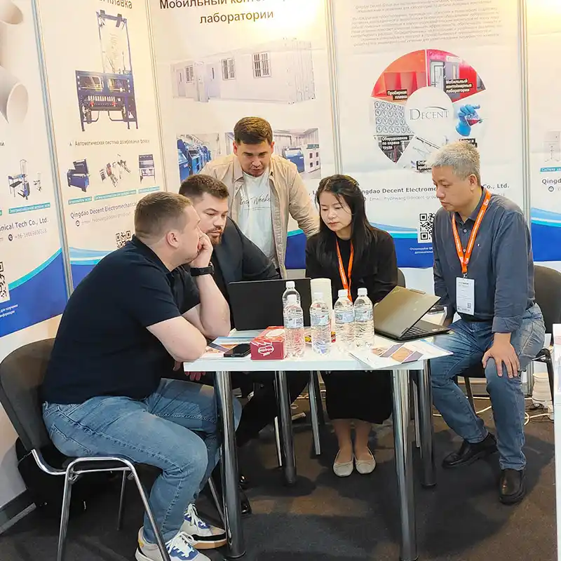 Qingdao Decent Group staff and potential customers discussing mineral laboratory solutions at a table with laptops at the DECENT exhibition booth, Mining and Metals Central Asia 2025.