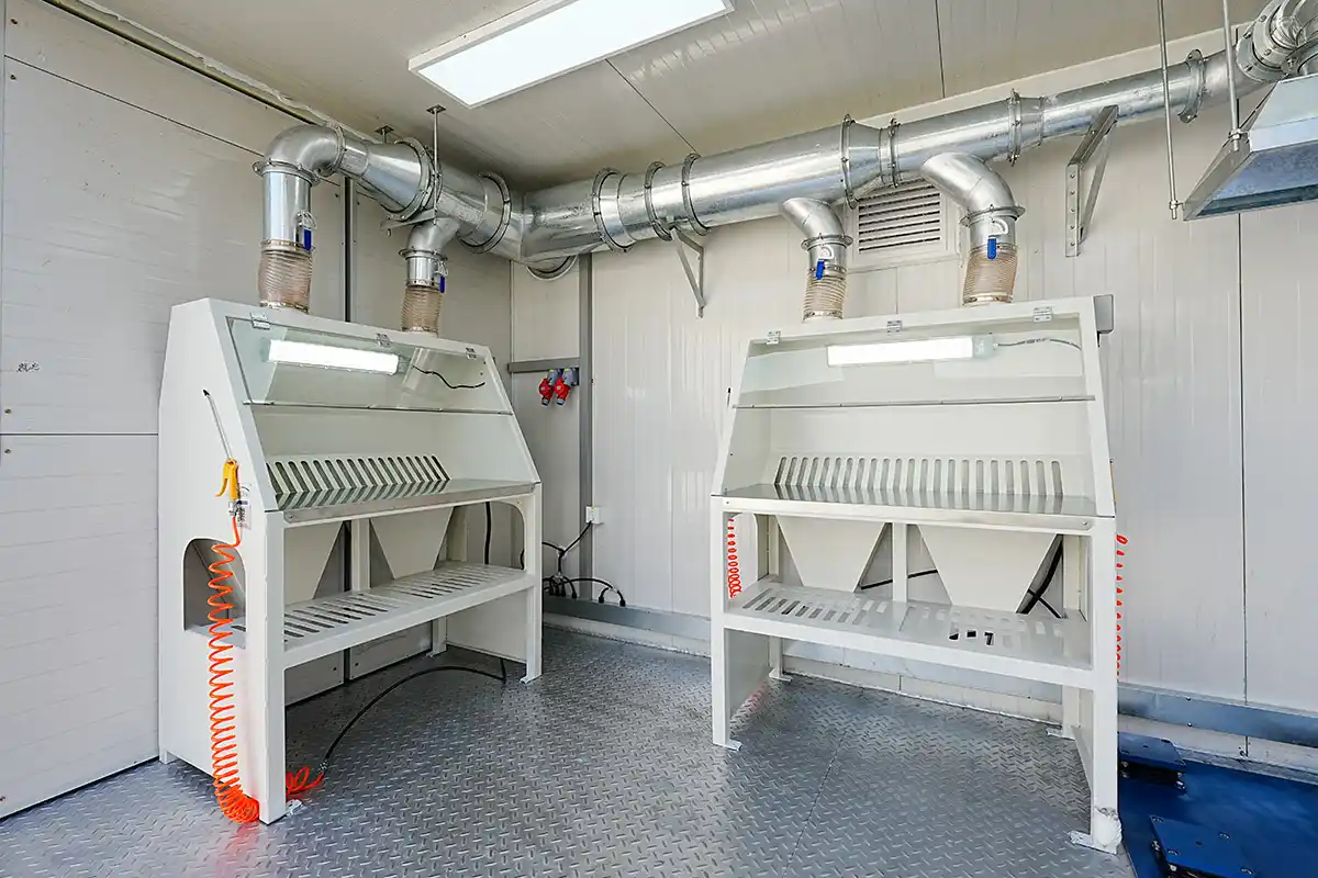 Two white sample preparation workbenches with safety hoods and overhead dust collection ducting inside a DECENT lab.
