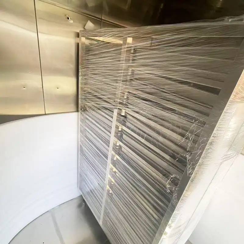 A large, multi-tray laboratory drying oven from DECENT, wrapped in plastic and placed inside a room with stainless steel walls.
